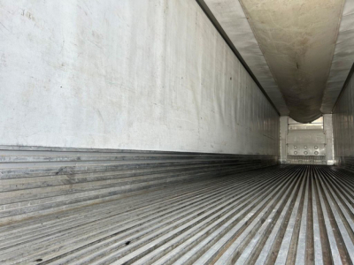 Trailer interior showing ribbed metal flooring and side walls of a refrigerated trailer.