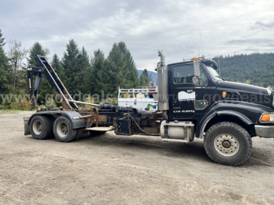 Sterling LT9500 truck in profile showing roll-off bed and chassis with black cab and chrome exhaust stacks.