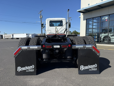 Rear view of a new Mack PI84T conventional daycab truck showing dual rear wheels and mudflaps with Bruckner's Truck & Equipment branding.