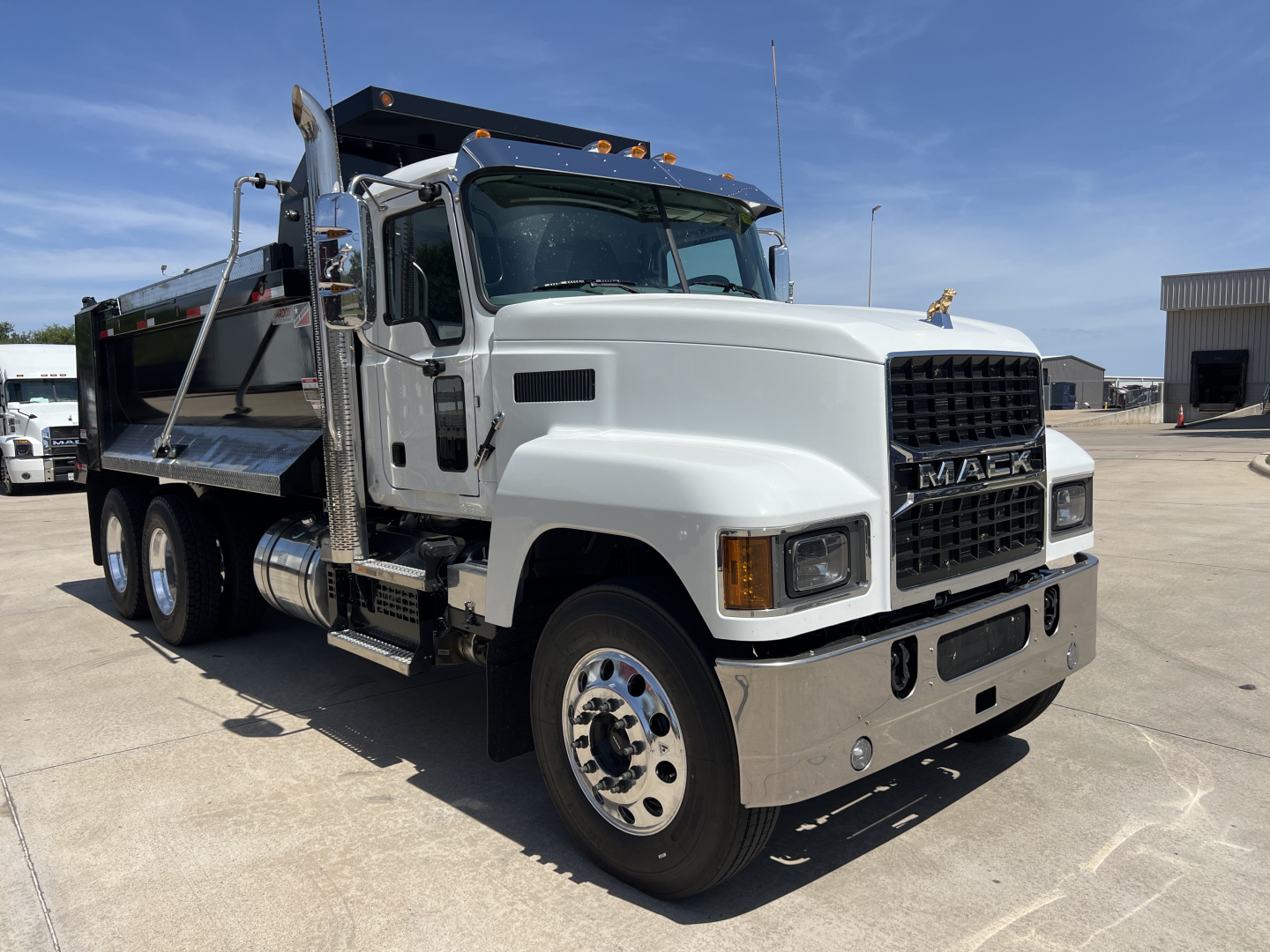 Mack PI64 dump truck in driveway showing front grille, cab, and dump bed with chrome bumper and steps.