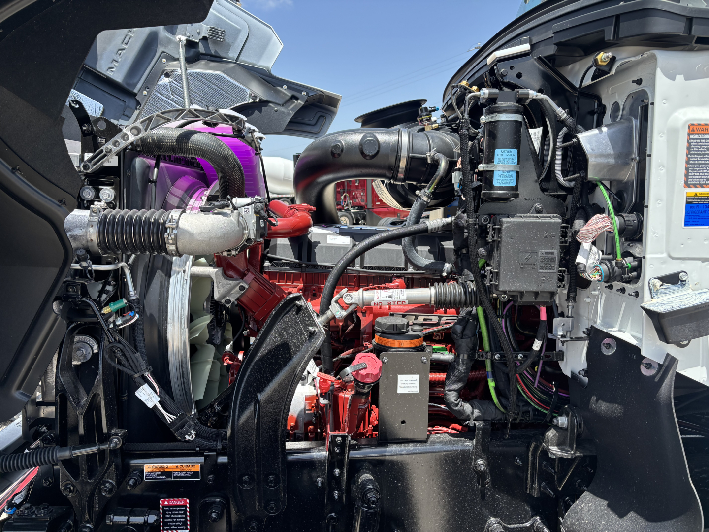 Mack PI64 engine bay showing red engine block, turbocharger piping, black hoses, and electrical components.