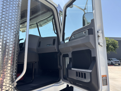 Truck cab interior and open door of a 2027 Mack PI64 showing entry for driver seat and dashboard area.
