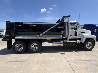 Mack PI64 dump truck side view showing black dump body, chrome tandem rear wheels, and chrome fuel tank.