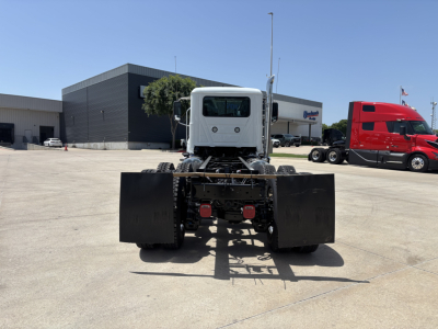 Front view of a white 2027 Mack PI64 dump truck chassis showing dual large rear tires and chassis components.