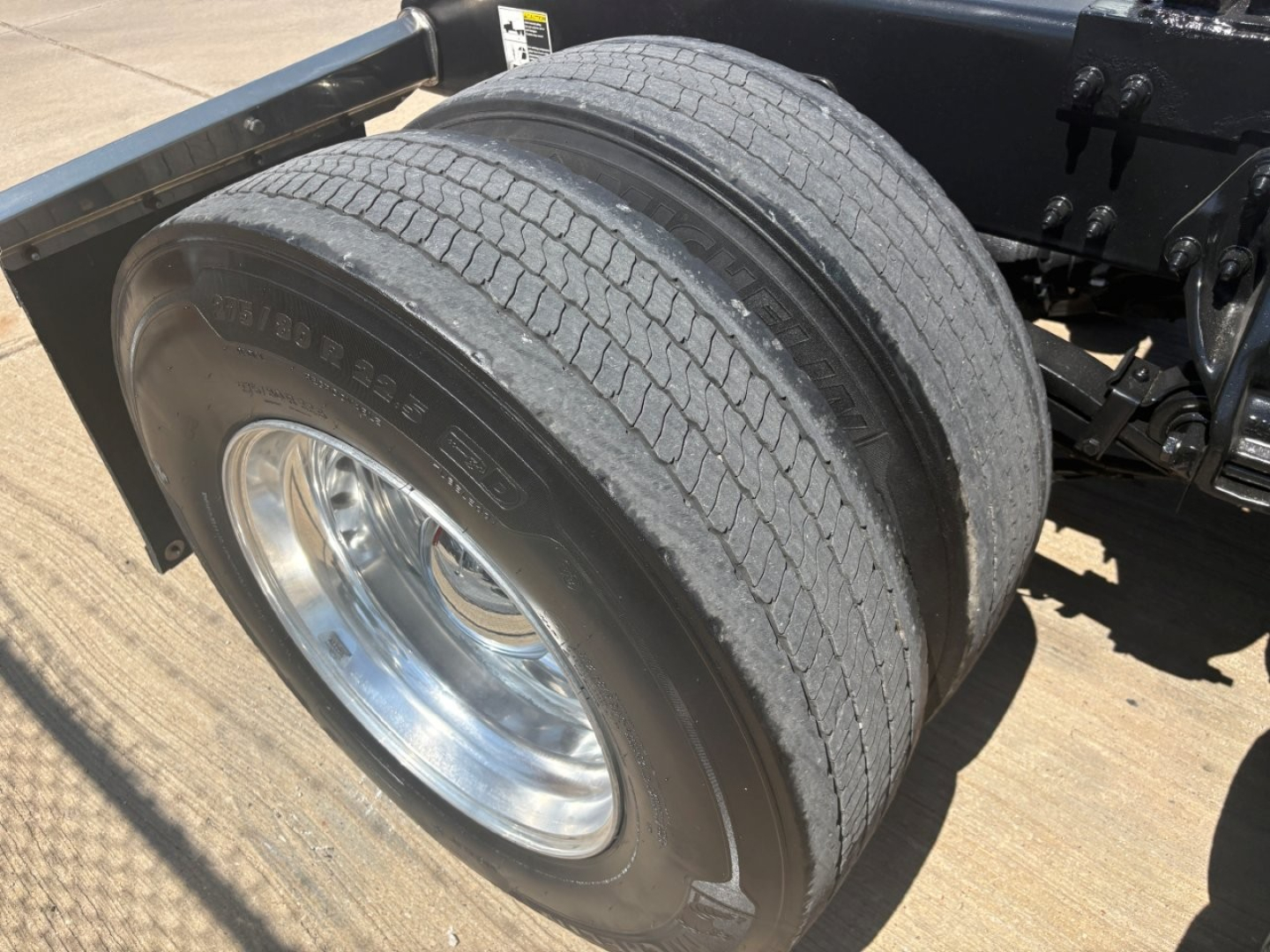 Peterbilt 579 truck rear dual tires view showing wheel, tire sidewall markings, and chassis frame.