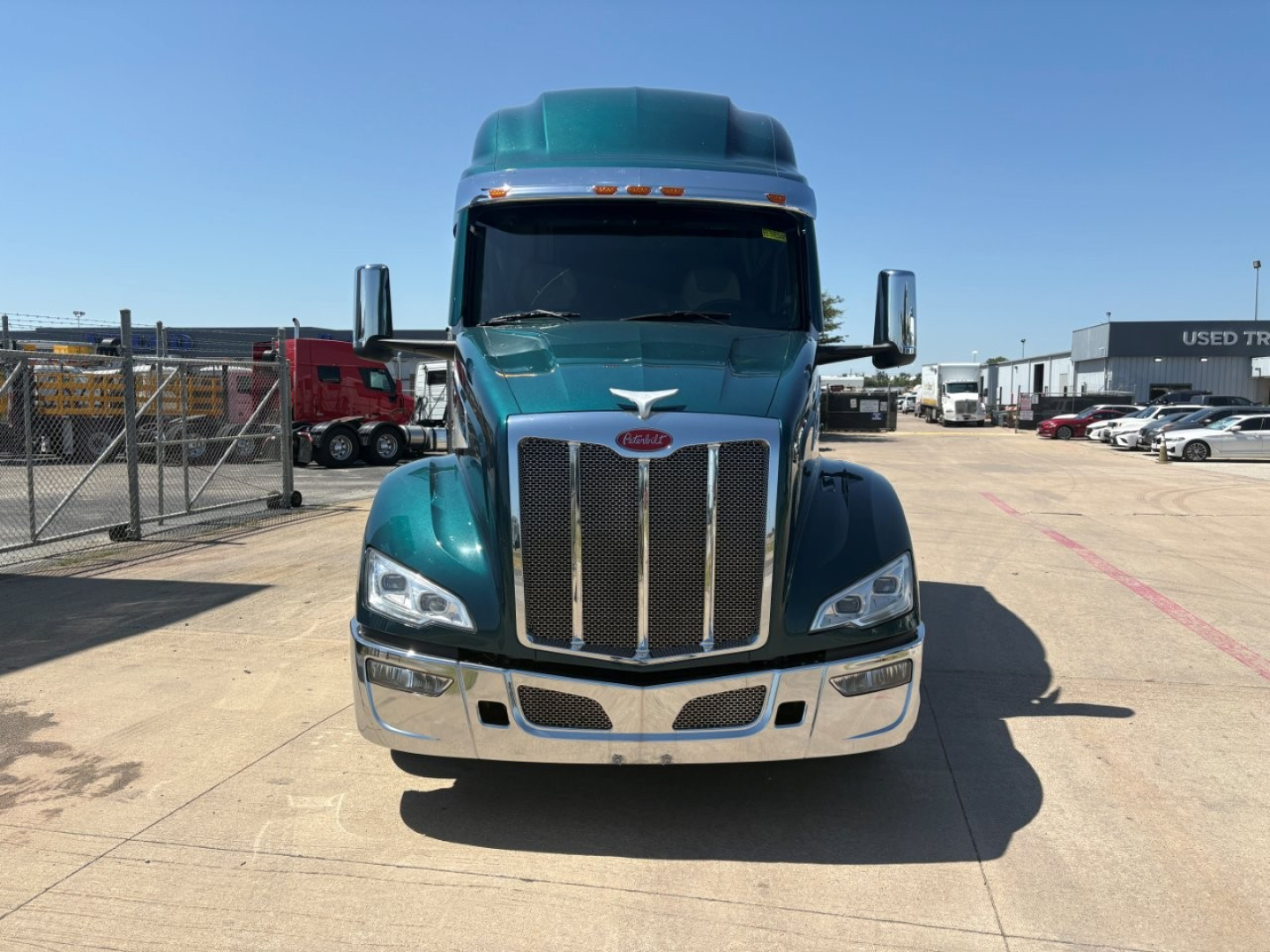 Peterbilt 579 truck front view in teal color, large chrome grille, headlights, bumper, and side mirrors visible.