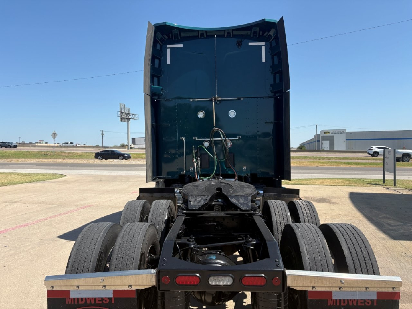 Rear view of a Peterbilt truck chassis showing dual rear axles and fifth-wheel area, cab back, taillights, and frame details.