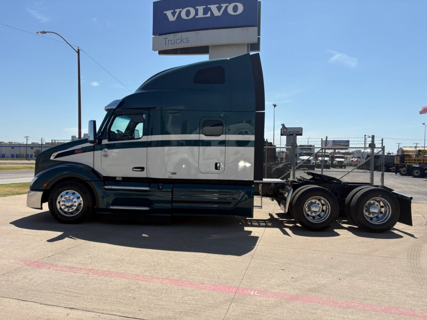 Peterbilt 579 tractor in side profile view showing sleeper cab, dual rear axles, and chrome wheels under a Volvo Trucks sign.