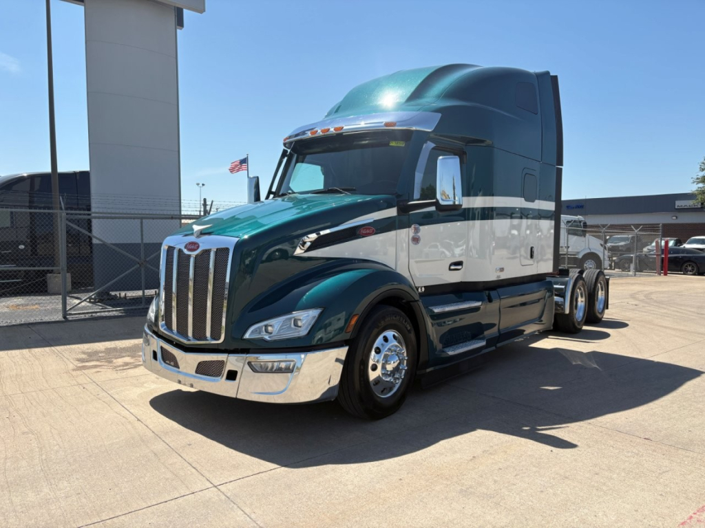 Peterbilt 579 conventional sleeper truck showing chrome grille, green cab, and black lower body with chrome wheels.
