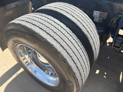 Peterbilt 579 truck front dual rear wheels showing tread and chrome rim with sticker and label nearby.
