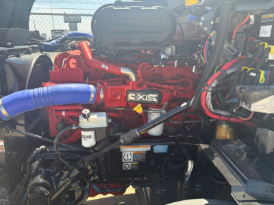 Peterbilt 579 engine bay with red 6-cylinder engine, blue turbo hose, and OEM components visible.