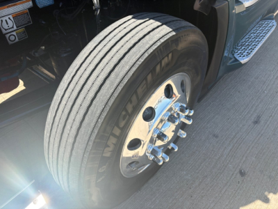 Peterbilt 579 front wheel and tire close-up showing Michelin tire and chrome lug nuts, part of a conventional sleeper truck.
