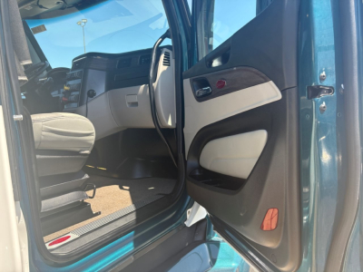 Peterbilt truck cab interior entry door open showing front seats, dashboard, and door panel. Part of blue exterior visible.