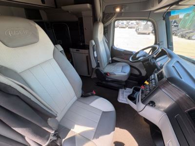 Peterbilt 579 truck interior showing steering wheel, dashboard, and front seats with light gray upholstery.