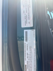 Vehicle identification label and spec stickers on a Peterbilt 579 door jamb showing VIN 1XPBD49X1SD680490 and stock B3750P along with barcodes.