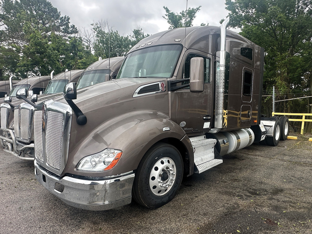 Kenworth T680 heavy-duty truck front-left view showing chrome grille, large side mirrors, sleeper cab, and fuel tanks.