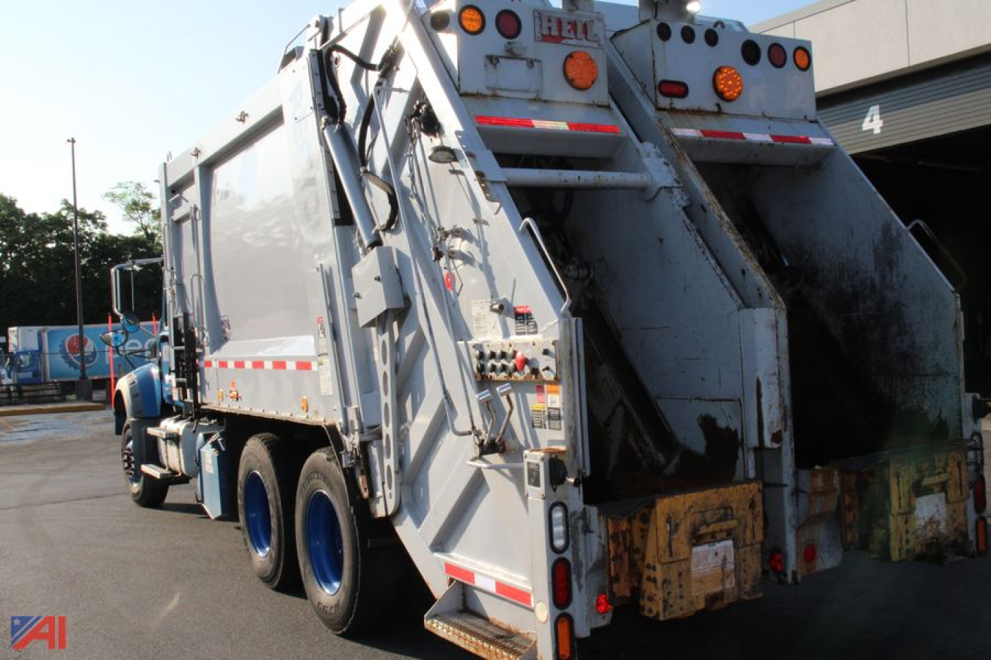 Rear and side view of a 2020 Mack Heil Granite Dual Hopper Packer truck in a used condition, with large stainless steel hopper bodies and rear unloading area.