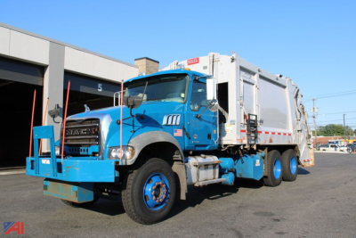 Truck in blue Mack Heil Granite Dual Hopper Packer body with large front bumper and dump-style rear hopper, side view showing lettering and components.
