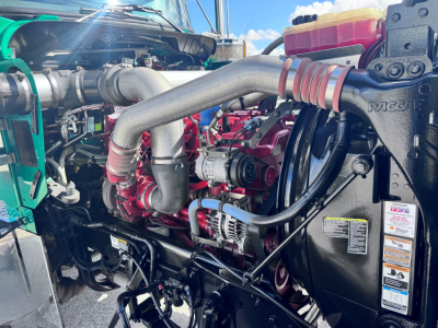 Kenworth W900L engine bay showing turbocharger, hoses, radiator hoses, and auxiliary components in a diesel engine compartment.