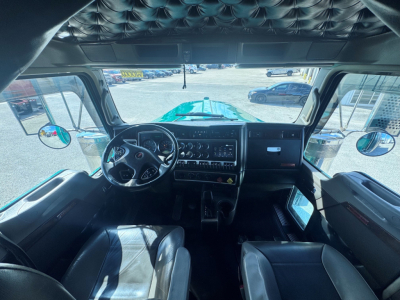 Kenworth W900L truck cab interior view from driver seat showing dashboard, steering wheel, and center console.