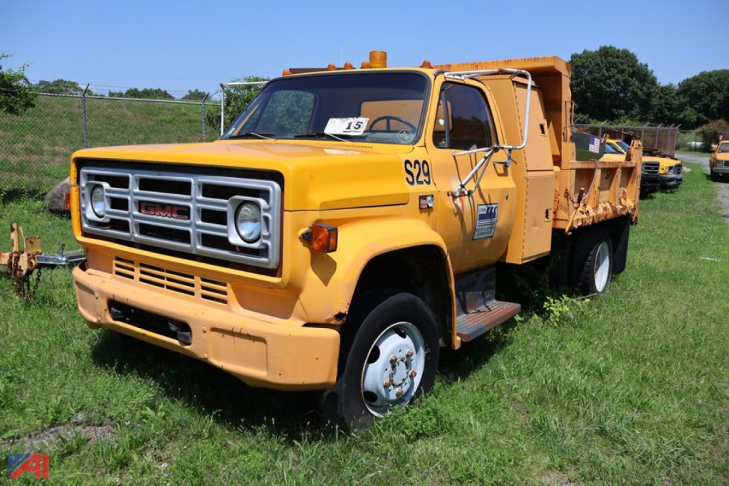 1990 GMC TopKick C6500 dump truck in yellow profile view showing front grille and dump bed