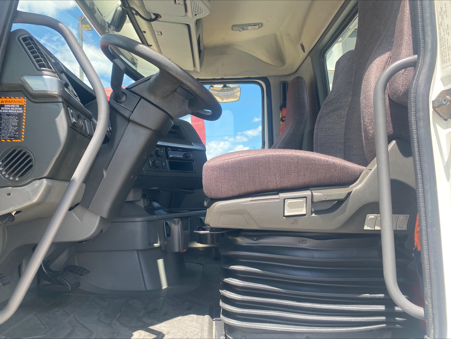 Truck cab interior of a 2019 Volvo VNL300 showing driver's seat, steering wheel, and dashboard from doorway view.