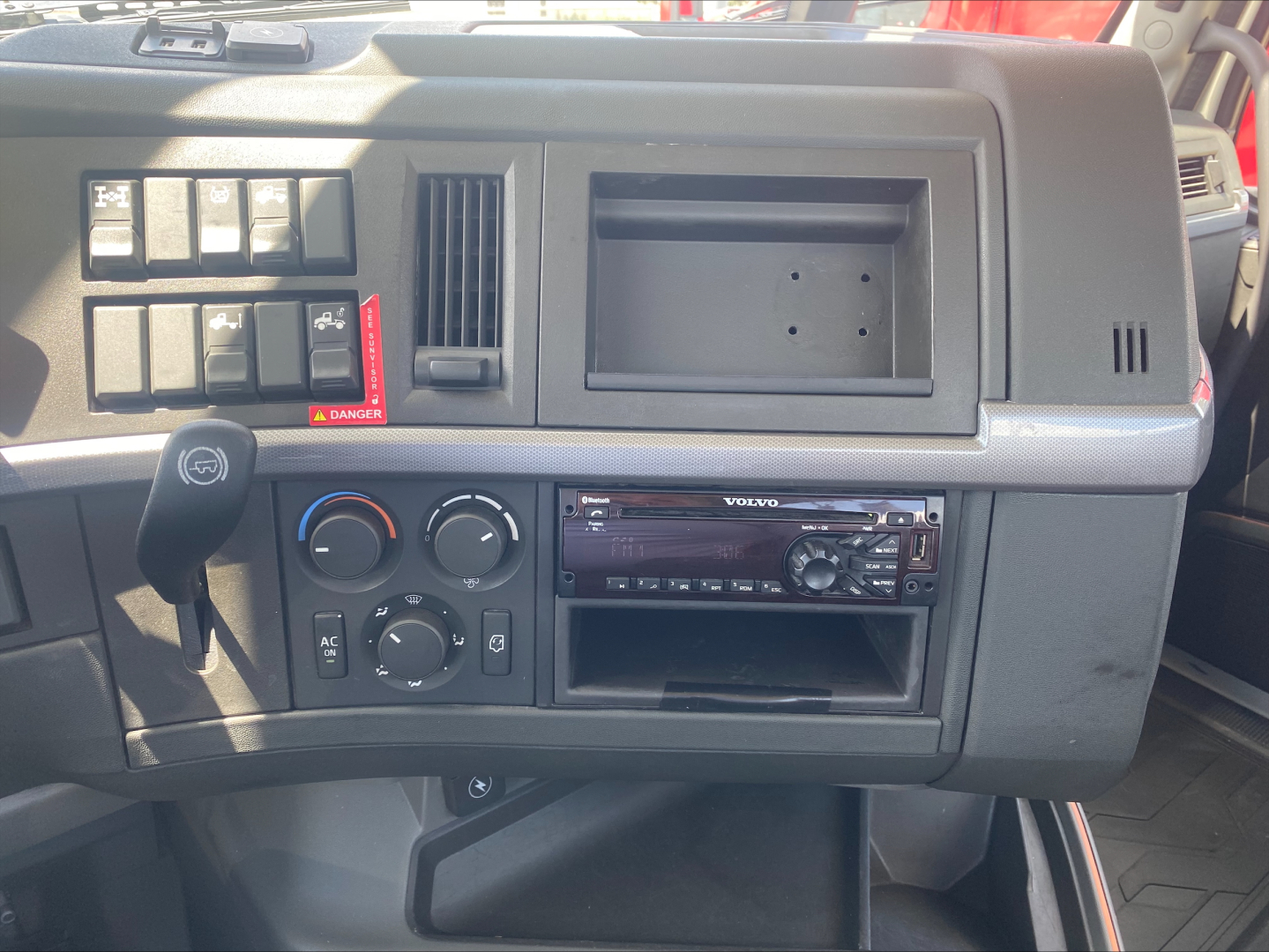Cabin dashboard of a 2019 Volvo VNL300 showing climate controls, radio tuner, empty radio slot, and various switches.