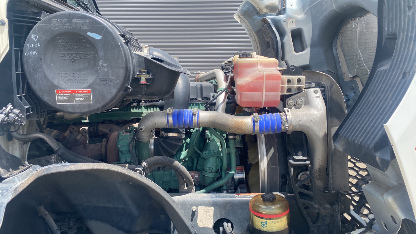 Volvo VNL300 engine bay showing coolant reservoir, hoses, and engine components in view.