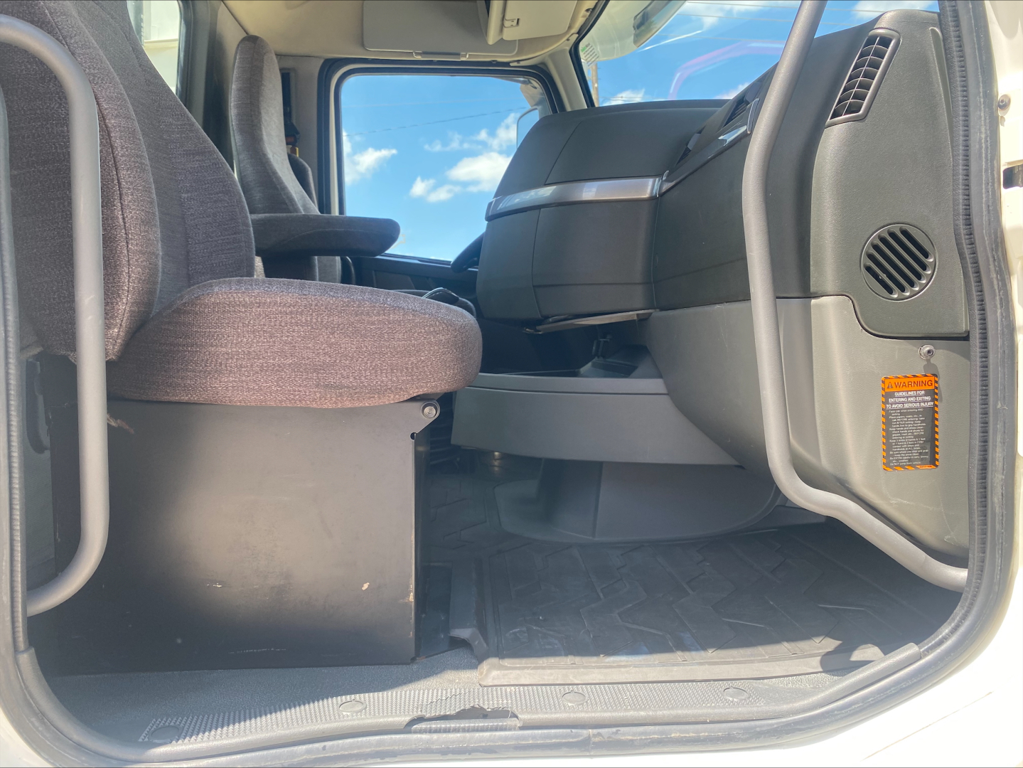 Cab interior of a 2019 Volvo VNL300 sleeper or daycab showing front seats and dashboard from the driver door sill perspective.