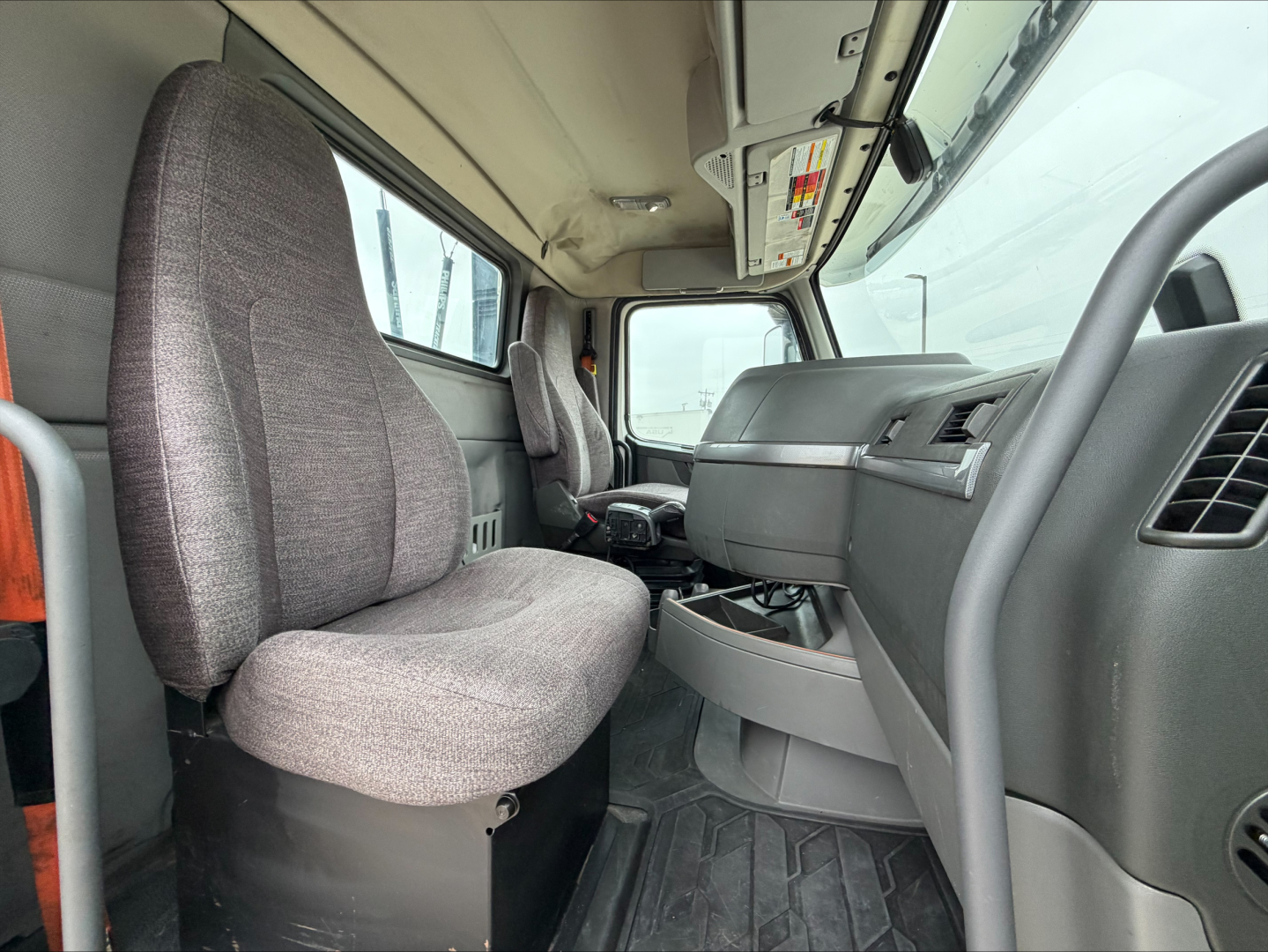 Cab interior of a 2019 Volvo VNL300 conventional daycab showing front seats and dashboard with steering wheel and center console.