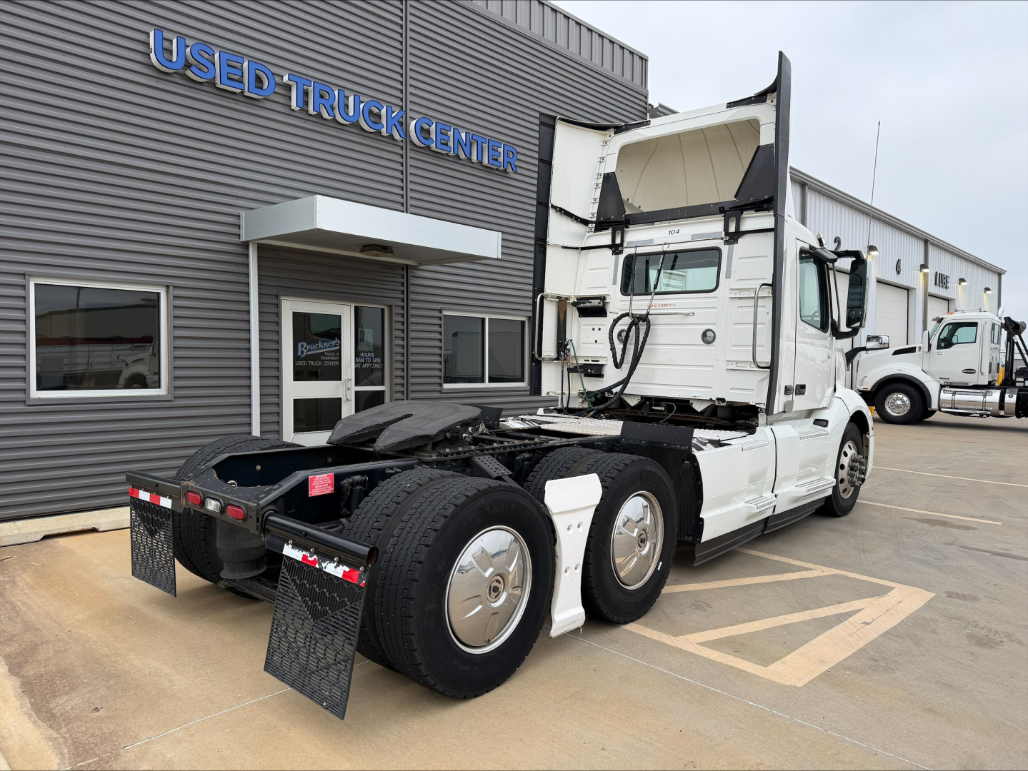Volvo VNL300 tractor unit in a used truck lot showing rear view and cab interior open.