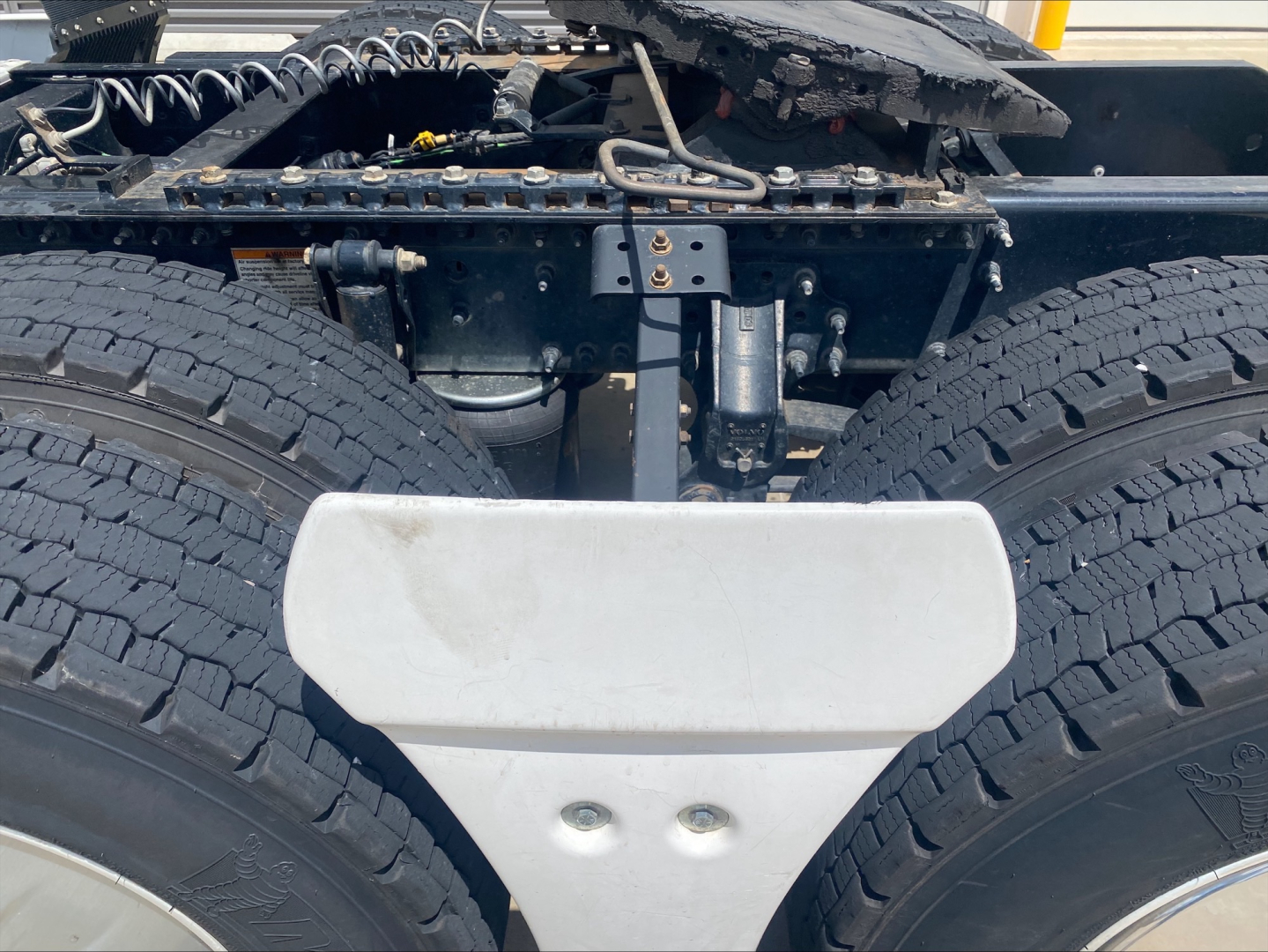 Volvo VNL300 truck chassis showing rear dual rear axles and metal frame, with a white mudguard/deflector and wheel treads visible.
