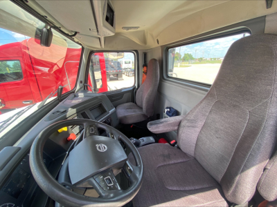Cab interior of a 2019 Volvo VNL300 truck showing steering wheel, driver seat, and passenger seat with grey fabric upholstery.