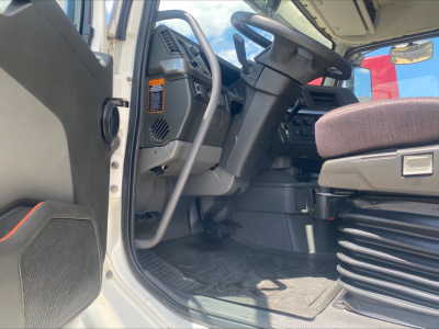 Volvo VNL300 truck cab interior view from open driver door showing steering wheel, dashboard, driver's seat, and floor mat.