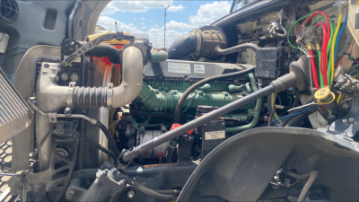 Volvo VNL300 engine bay showing green diesel engine with hoses and wiring harness in view.