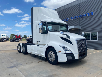 Volvo VNL300 tractor in white, front three-quarter view, with raised sleeper cab and grille, parked outside a truck center.
