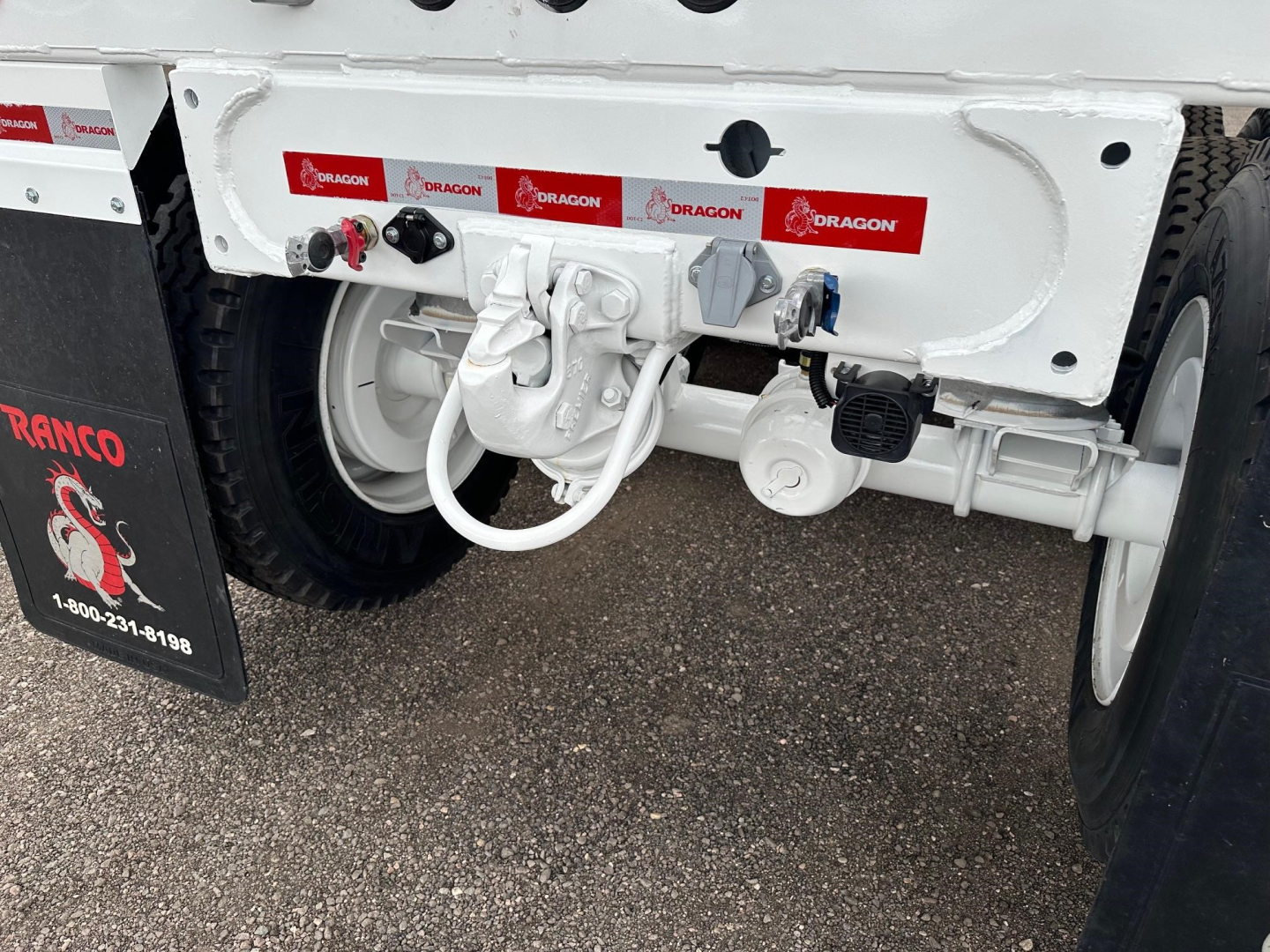 Rear undercarriage of Dragon Ranco trailer showing hydraulic components, coupler, and hoses with red Dragon stickers.
