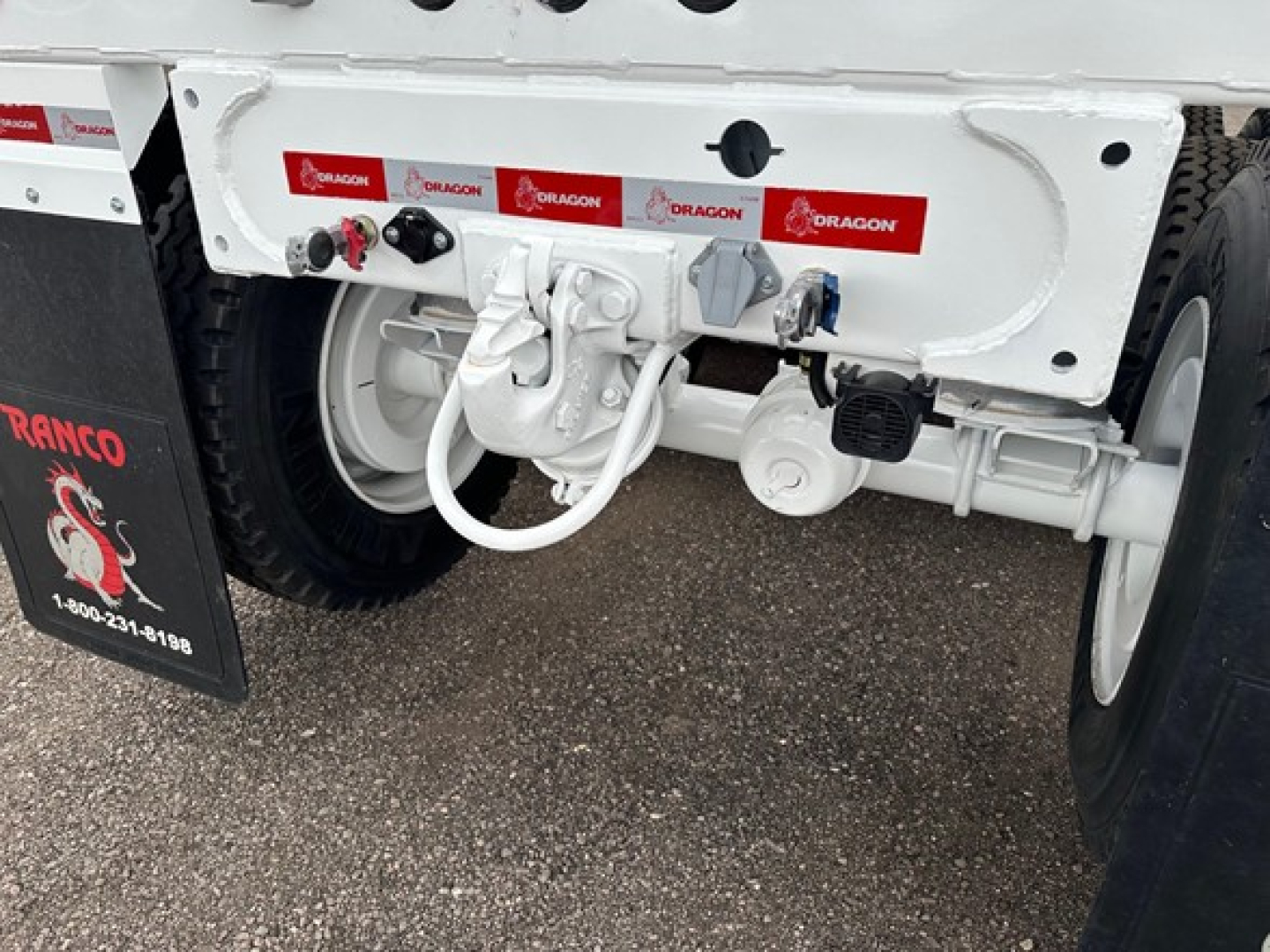 Trailer hitch components and undercarriage with white mechanical fittings and Dragon stickers visible