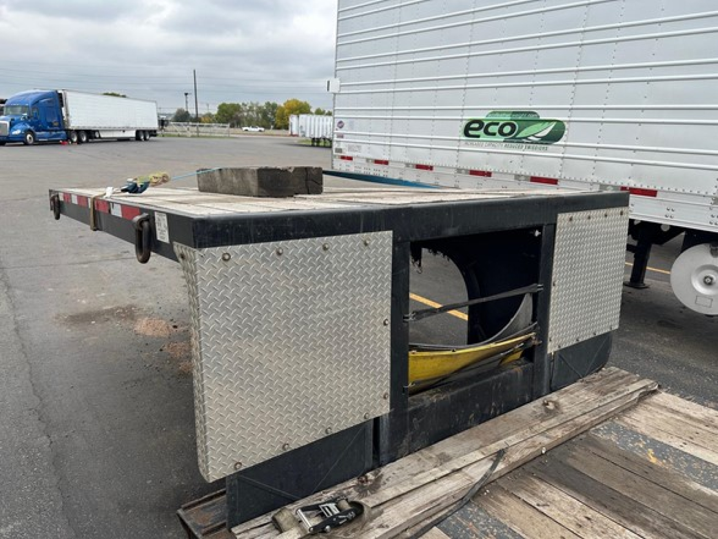 Flatbed trailer with diamond plate toolbox panels and open center cutout showing hydraulic hoses and frame, 2024 Fontaine Renegade listing.