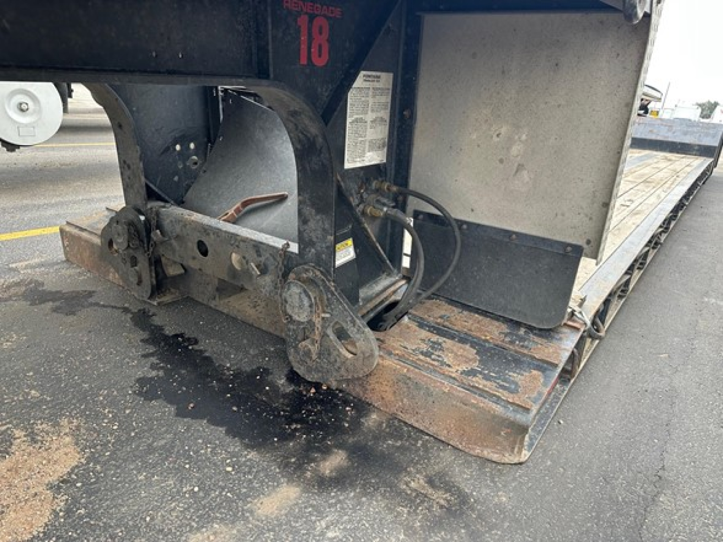 Fontaine Renegade trailer hitch area showing steel frame, ramp, and hydraulic/air lines with rusted steps and label; numeric '18' tag visible.