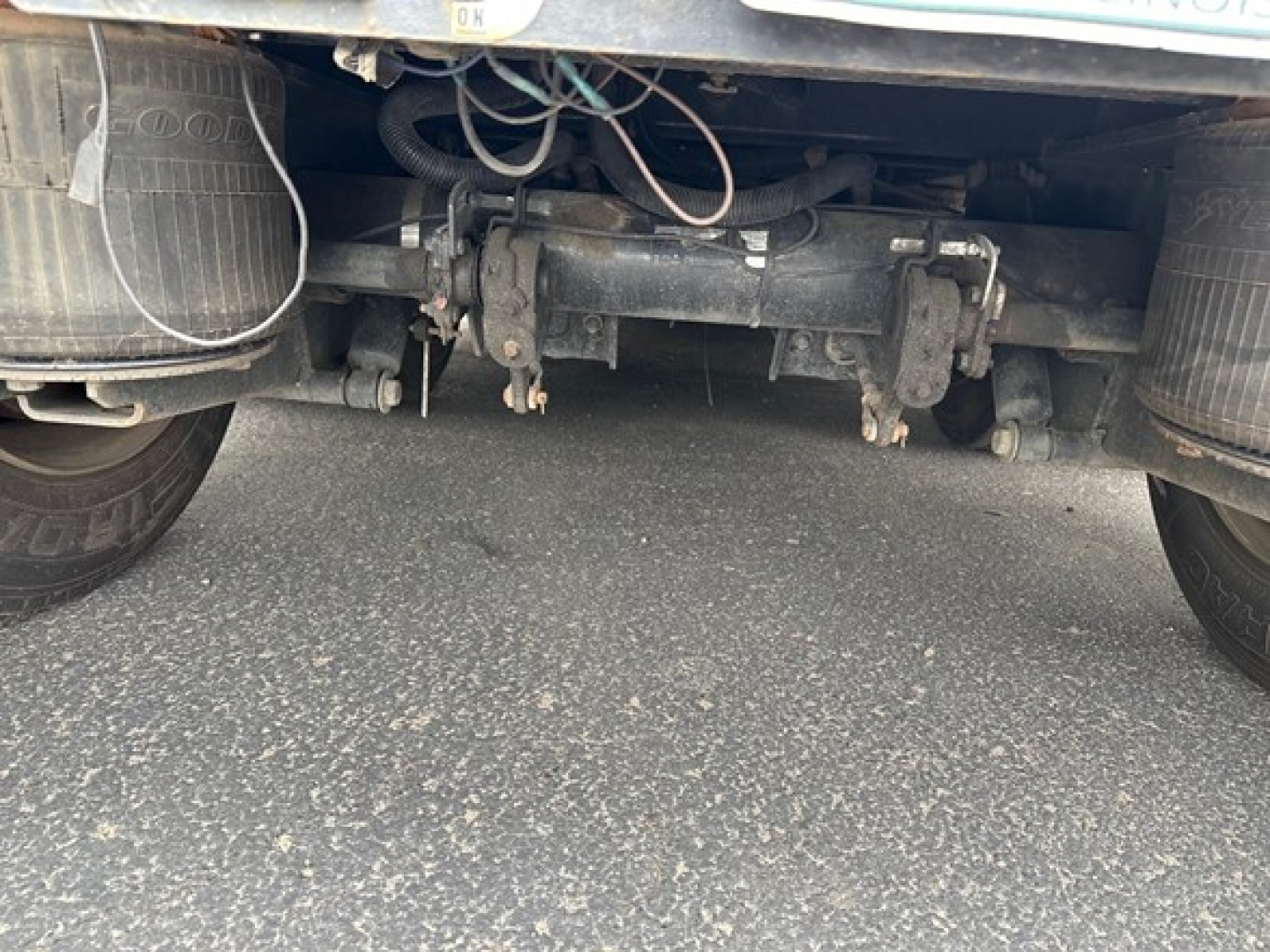 Rear view of tandem axle Fontaine Renegade trailer showing suspension and undercarriage components, including axles, differential housing, and wiring harnesses.
