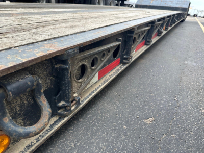 Bottom edge of a Fontaine Renegade trailer with deck shown and various support fittings visible along the side, including circular cutouts and red reflectors.