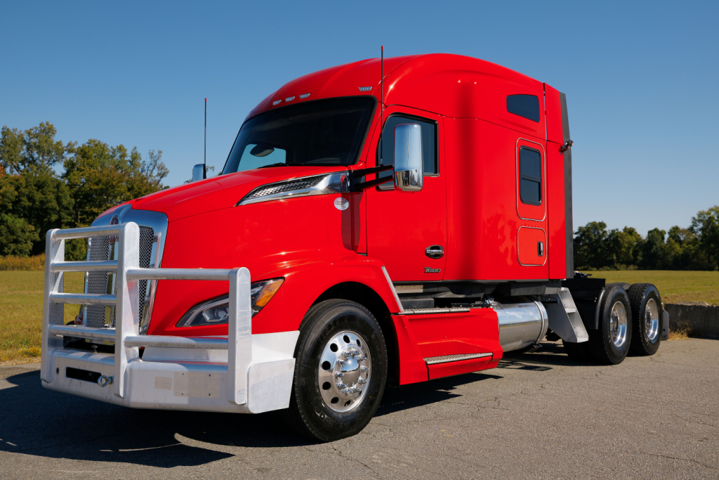 Kenworth T680 truck in red, frontal side view, with grille guard and dual rear axles visible.