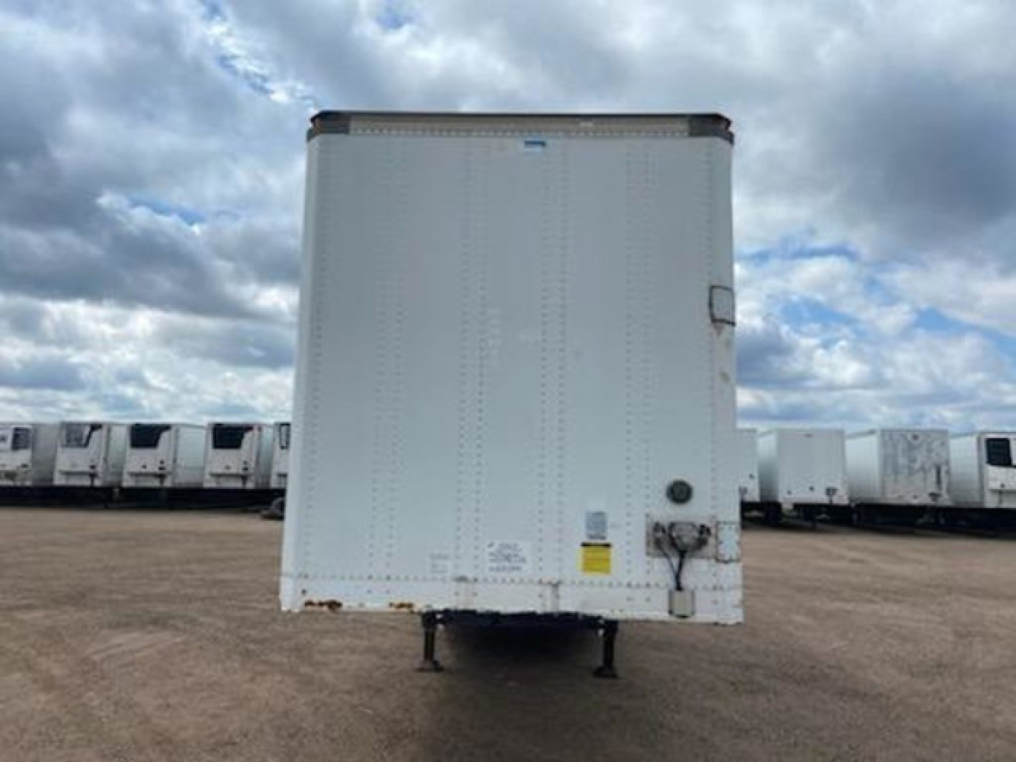 Trailer rear of a 2014 Stoughton van with raised cargo area, white exterior, rear doors, and standard undercarriage in a lot with other trailers.