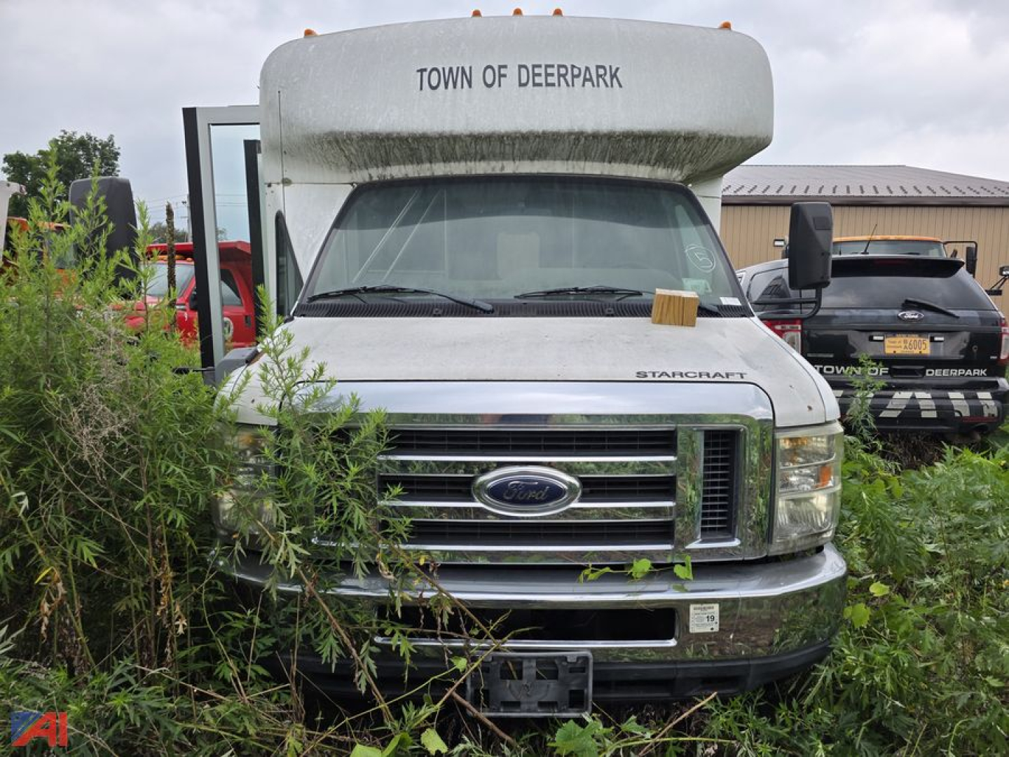 Ford E-350 Starcraft wheelchair bus front view with overgrown plants around grille and town of deerpark text on top of the bus