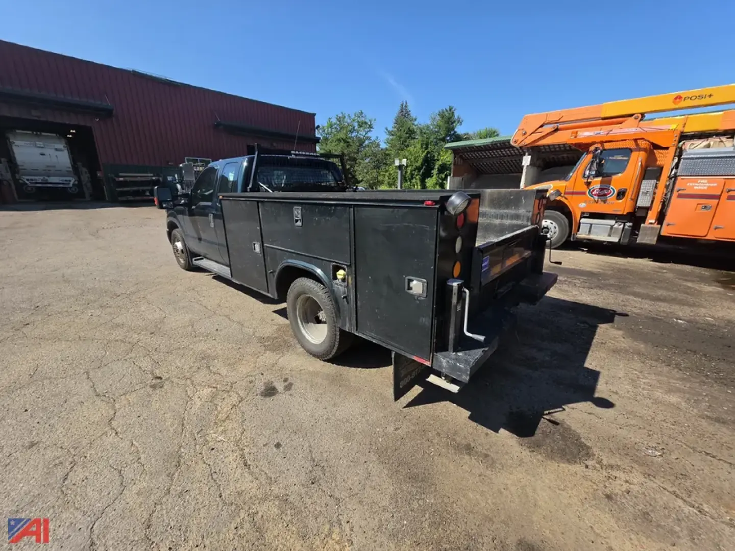 Ford F-350 Super Duty utility truck bed (flatbed) with large metal toolbox compartments and rear tailgate, seen from rear-left angle in a lot.
