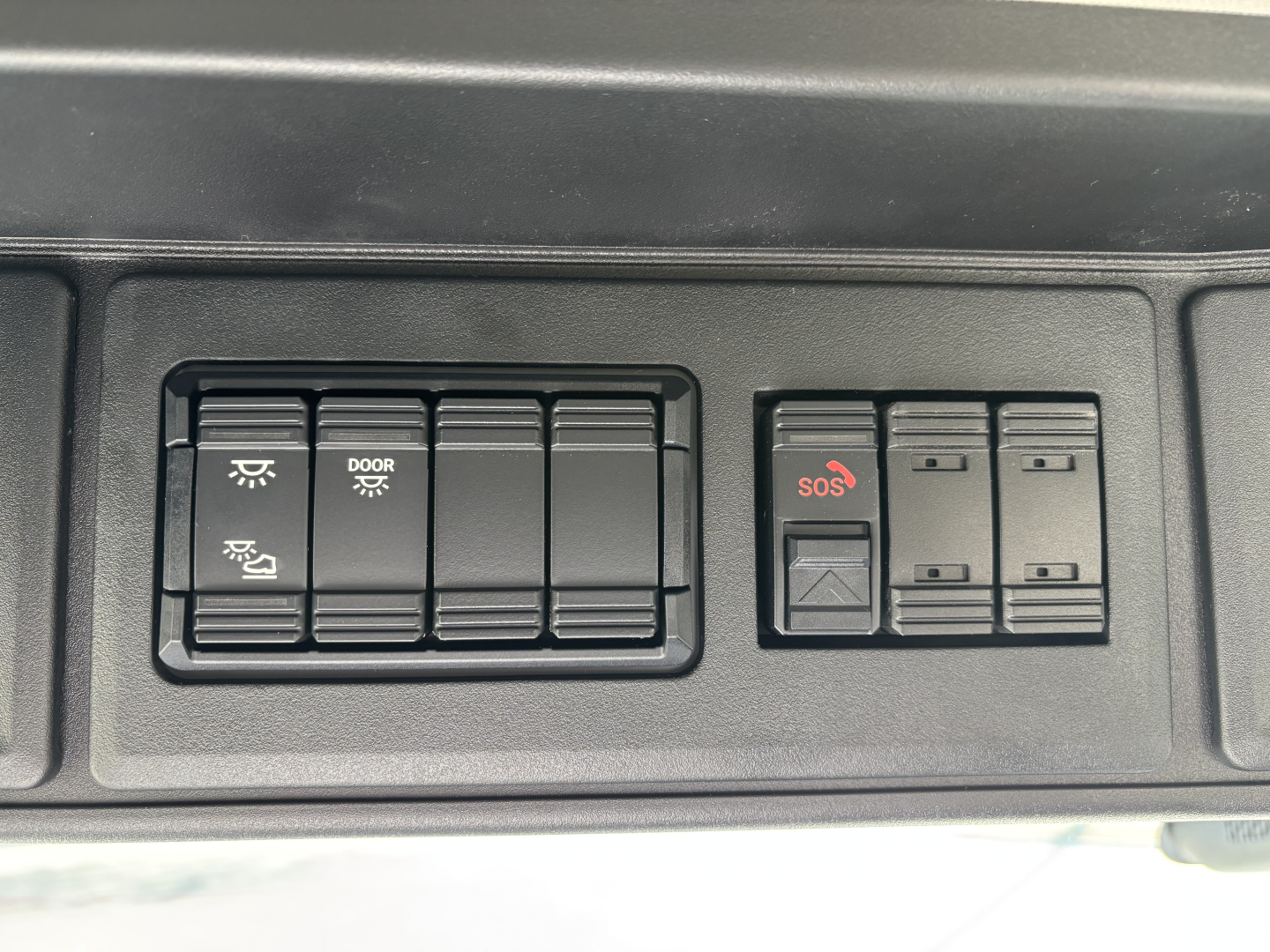 Console panel showing rocker switches including door/open indicators and SOS button in a Mack AN64T cab.