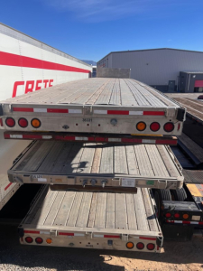 Trailer deck viewed from rear showing multiple stacked flatbed sections with tail lights and reflective strips.