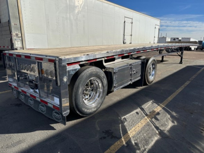 Mac polished all aluminum flatbed trailer with dual rear axles and wooden deck, side chain box, and rear lights