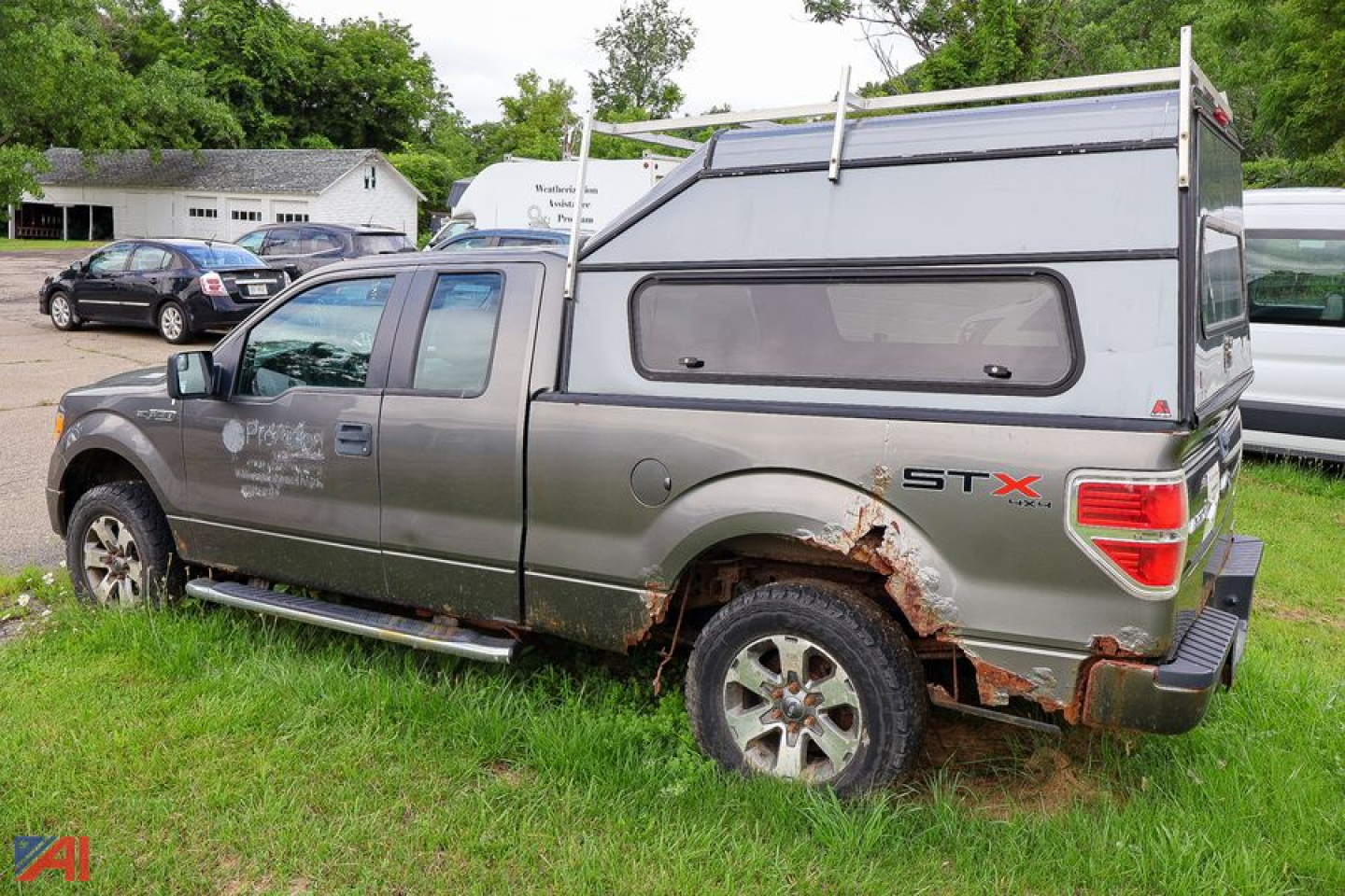 Ford F-150 crew cab pickup with cap, side view showingSTX badge and rust on rear wheel well